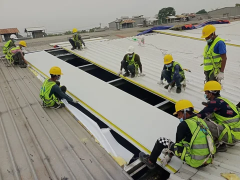 Construction crew installing an industrial roof system